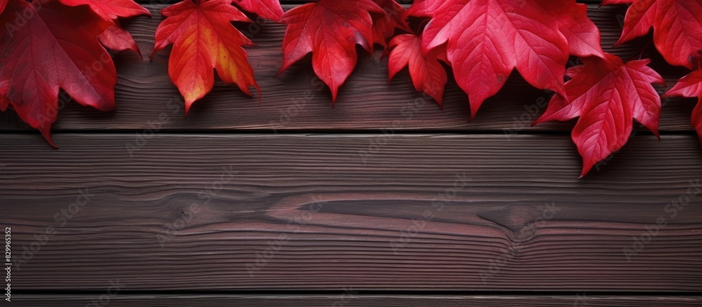 Poster autumn leaves in red hues surround a wooden surface creating a beautiful composition perfect as a co