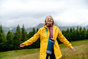 Smiling senior woman on a hiking trip on a hill.