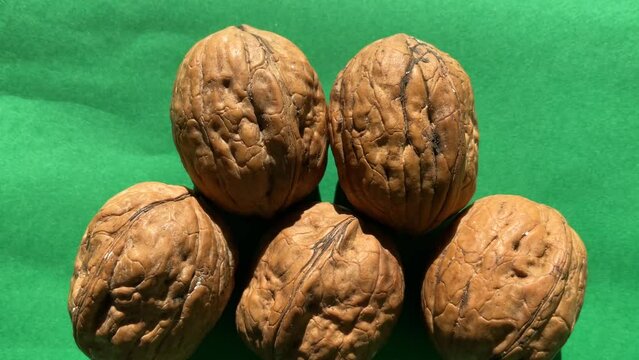 Slow upward pan of walnuts on green background