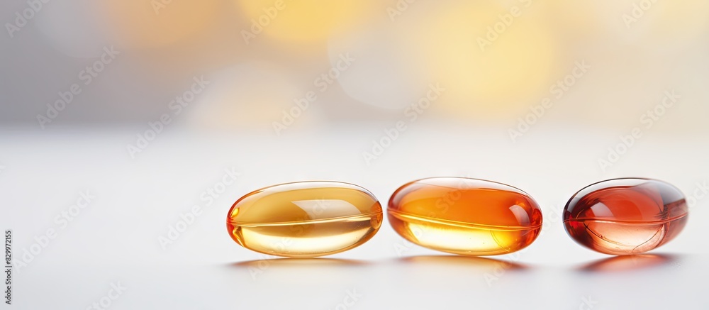 Poster Close up high resolution copy space image of three Omega 3 capsules isolated on a white background surrounded by a multitude of other capsules on a blurred background This image conveys the concept o