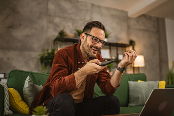 Adult caucasian man work from home on laptop and talk on mobile phone