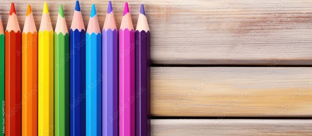 Poster A colorful array of pencils with a painted rainbow on white paper set against a purple wooden background creating a captivating copy space image