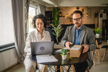 woman and man colleagues check shipment on laptop at cafe