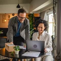 woman and man colleagues check shipment on laptop at cafe
