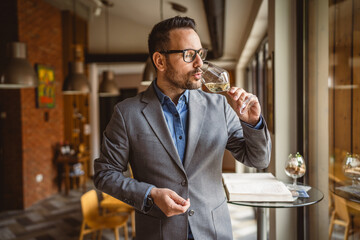 Adult man stand in a winery and drink glass of wine