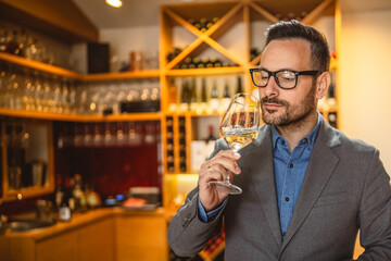 Adult man stand in a winery and smell glass of wine