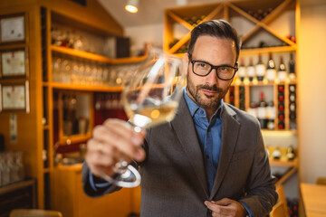 Adult man stand in a winery and hold glass of wine