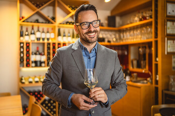 Adult man stand in a winery and hold glass of wine