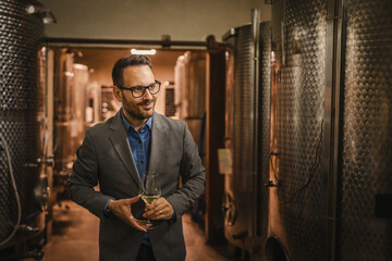 Adult man stand sommelier in basement and hold glass of wine