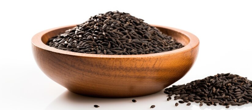 Copy space image of black cumin seeds presented in a wooden bowl isolated on a white background The pile showcases nigella sativa seeds captured from various angles creating a diverse and visually ap