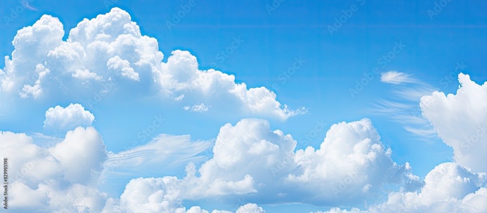 Poster During the daytime the sky is adorned with serene and tranquil puffy clouds against a backdrop of a vibrant blue color Available as a copy space image