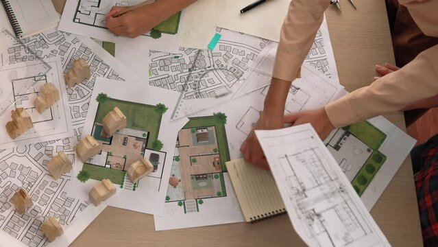 Architect and safety engineer discussion about building construction use blueprint on table with architectural document, measurement tool and wooden block scatter around at modern office. Delineation.