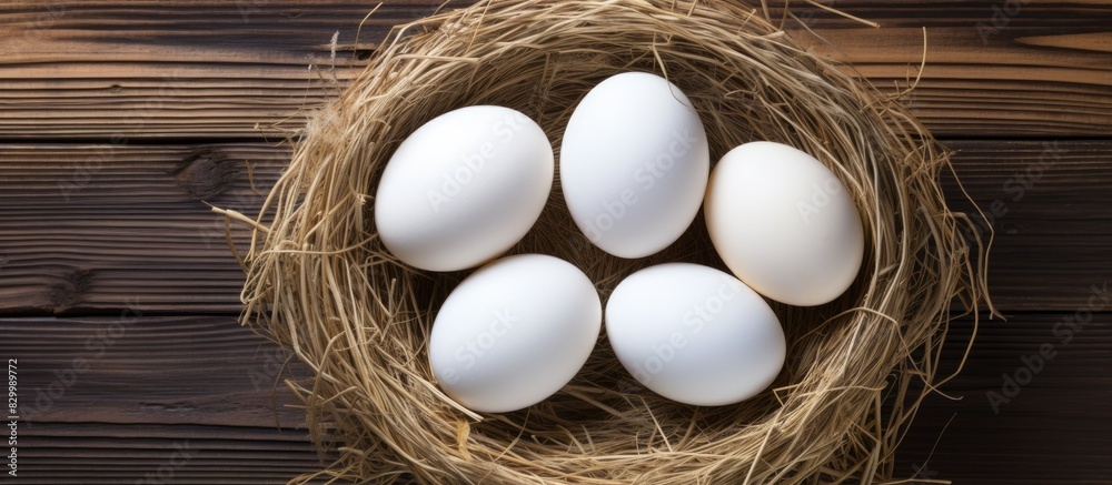 Poster Copy space image of white Easter eggs in a nest viewed from the top positioned on a wooden background providing room for text or words