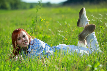 A girl relaxing on the grass on a sunny summer afternoon. Joy, happiness, serenity. Resting on the grass.