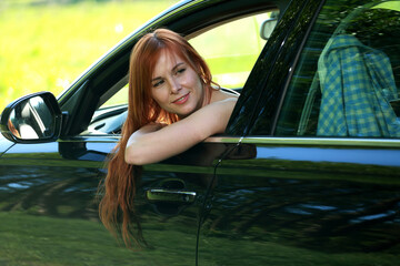 A girl poses for the camera with her car in nature. Joy, happiness, serenity. A girl with a car in nature.