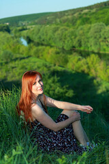 A girl in a red blouse and white jeans poses for the camera in nature. Joy, happiness, serenity. A girl poses for a photographer in nature.