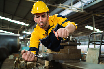A man in a yellow and blue uniform is working on a machine. He is wearing a yellow helmet and a...