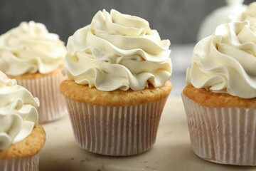 Tasty cupcakes with vanilla cream on table, closeup