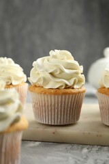 Tasty cupcakes with vanilla cream on grey table, closeup