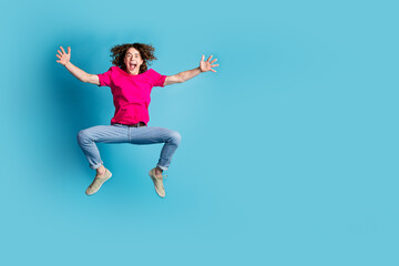 Full length portrait of nice young man jump empty space wear t-shirt isolated on blue color background