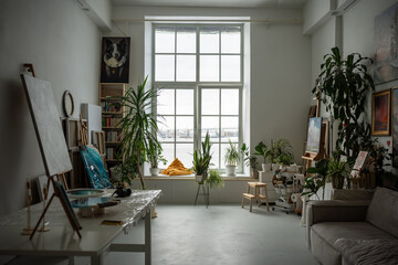 Cozy creative artist workplace with easel, oil artwork painted on canvas. Painter home art studio...