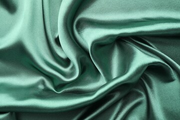 Crumpled green silk fabric as background, top view