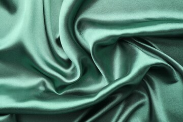 Fototapeta premium Crumpled green silk fabric as background, top view