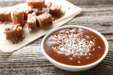Caramel sauce with sea salt in bowl on wooden table, closeup