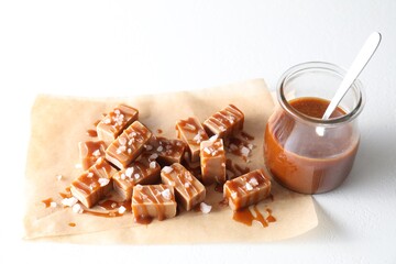 Tasty candies, caramel sauce and salt on white table