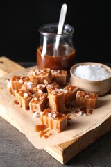 Tasty candies, caramel sauce and salt on grey table, closeup