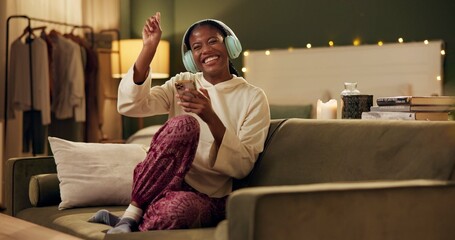 African woman, headphones and phone on couch with smile, singing or dancing to music in home living...