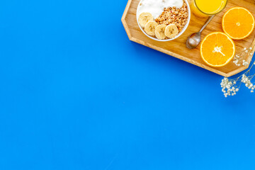 Healthy granola with banana and orange juice for colorful breakfast on blue background top view mock-up