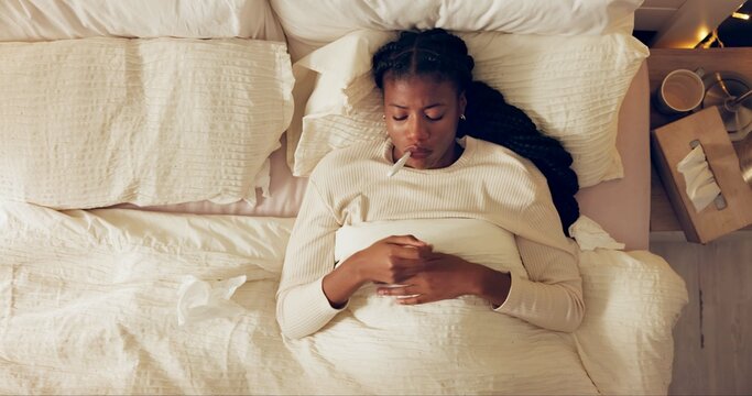 Woman, thermometer and mouth with sick in bed with tissue, flu and temperature check for fever in home. African person, medical tool and top view with blanket in bedroom for illness, health and virus