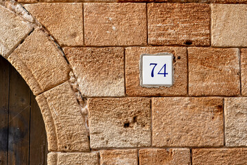 Historic Stone Wall with House Number 74 - Traditional Mediterranean Architecture Detail