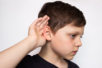 A child puts his hand to his ear and listens, isolated on a white background. Hearing problems, ear...
