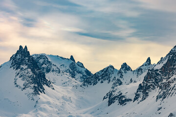Snow-covered mountain peaks under cloudy sky