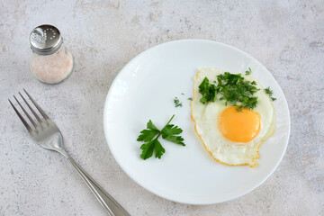 a plate of fried egg and parsley on a table with a fork 