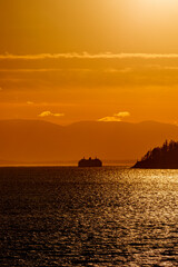ferry boat or ship round Bowen Island just before  sunset with orange skies near Vancouver, Canada,