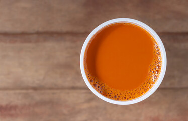 Hot milk tea in a white cup on wooden table background