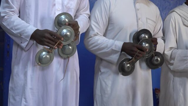 Close-up of moroccan musicians performing traditional folk music by krakeb musical instrument used as the rhythmic aspect of Gnawa music