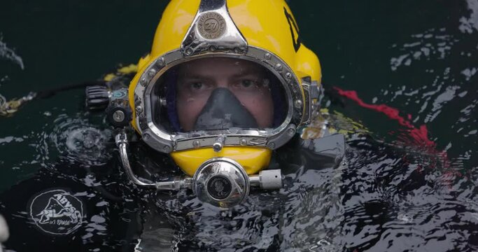 Commercial diver in helmet gazes at camera