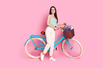 Photo of cheerful lovely cute woman wear stylish clothes ride bicycle isolated on pink color...
