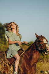 A young beautiful woman rides a horse in the forest in autumn. Horseback riding in the evening in...