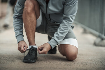 A man tying shoelaces on sport shoes in the city center park before cardio workout, running.  Health and Lifestyle in big city life concept.