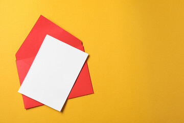 Blank sheet of paper and letter envelope on orange background, top view. Space for text