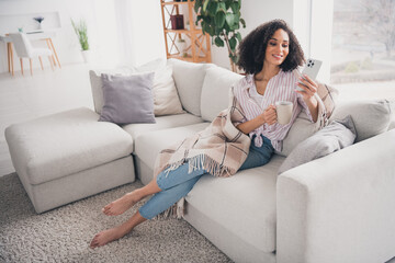 Obraz premium Full length photo of pretty cheerful lady wear casual shirt drinking coffee chatting modern device indoors room home house