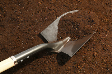 Metal shovel on fertile soil. Gardening tool