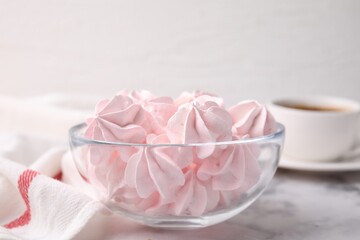 Tasty meringue cookies in bowl on white marble table