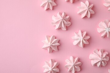 Many tasty meringue cookies on pink background, flat lay. Space for text