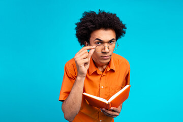 Photo of funky suspicious guy dressed orange shirt arm specatacles reading book looking you...